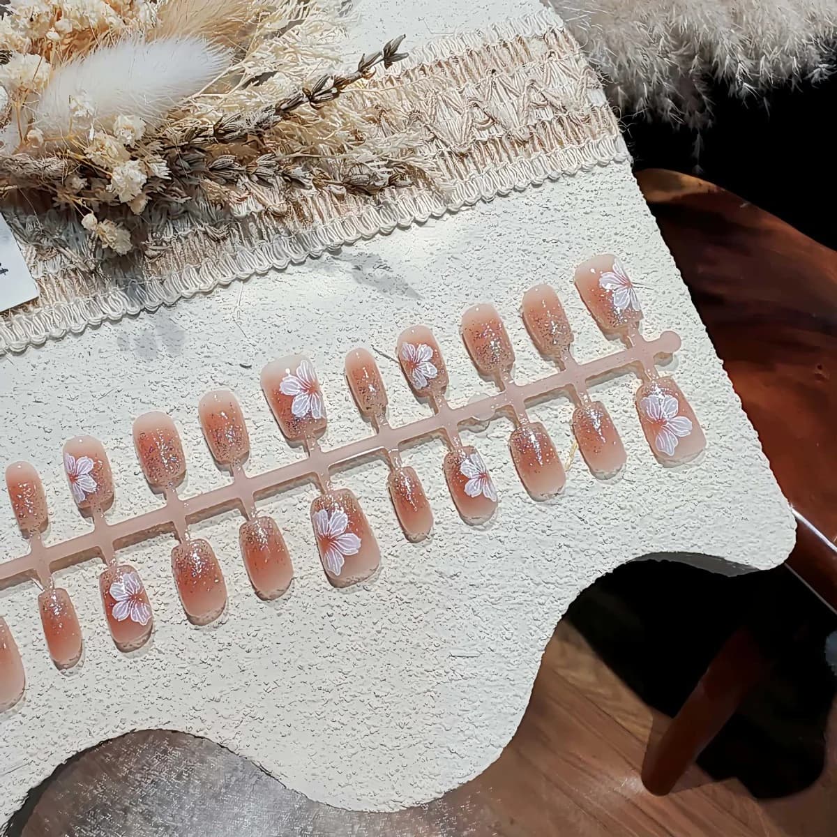 أظافر صناعية بيضاوية قصيرة بطرف فرنسي وتصميم زهري لامع